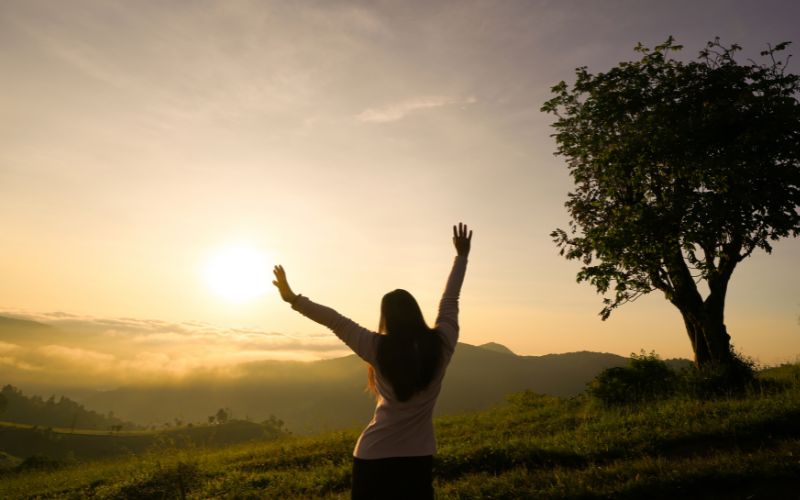 woman open arms at sunrise