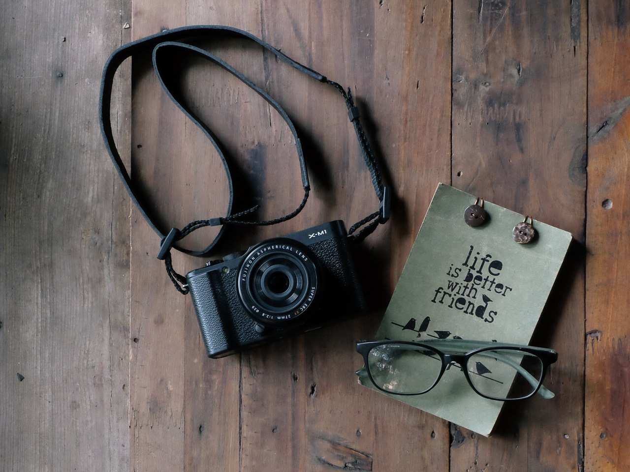 An image of a camera, glasses and a postcard