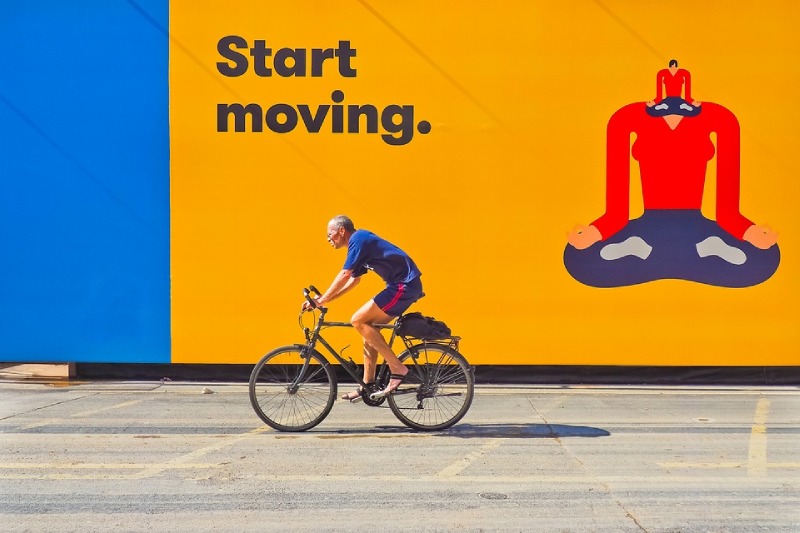 An image of an old man cycling against a painted wall