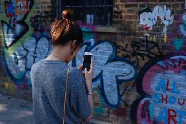 woman capturing pictures of a wall graffiti