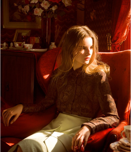 model sitting on a red chair and looking out to the side window - portrait photography smaple pose