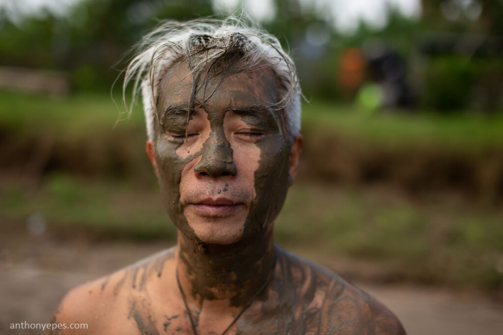 asian old man's face painted with mud