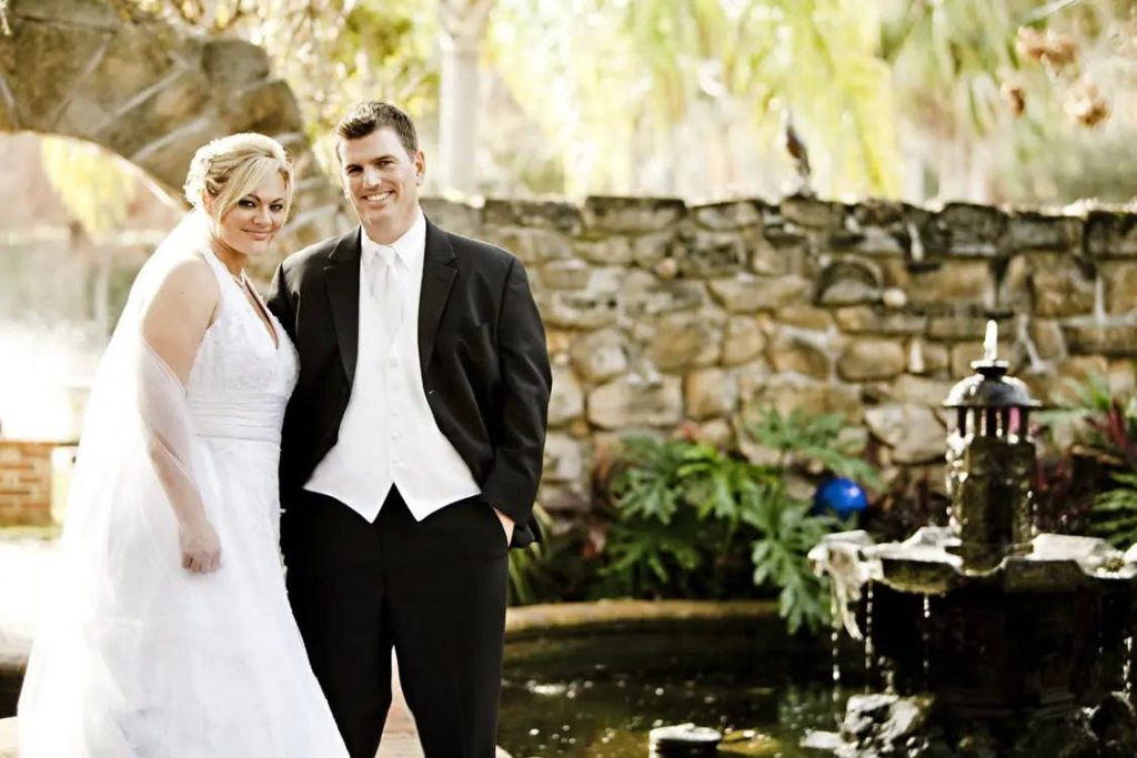 couples wearing wedding dress standing beside a fountain
