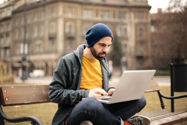 man wearing a beanie working on a laptop