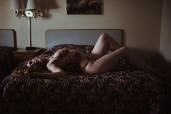 female model on a bed wearing skin colored bikini