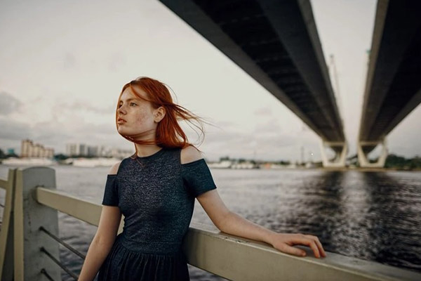 girl leaning on a river bridge