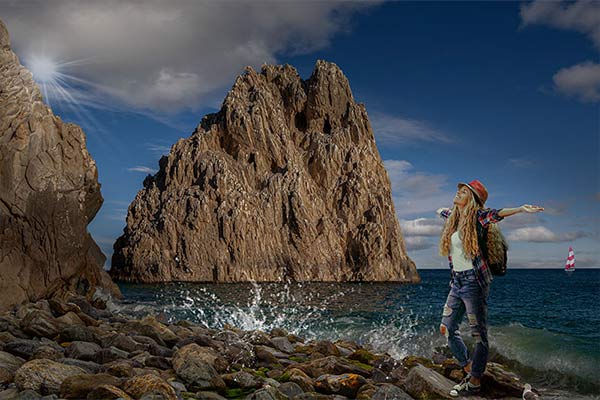 A woman posing against a natural water and rocky backdrop with her arms spread out and face upwards