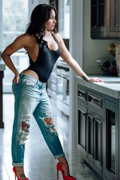 Model standing with one hand on hip while the other rests on counter