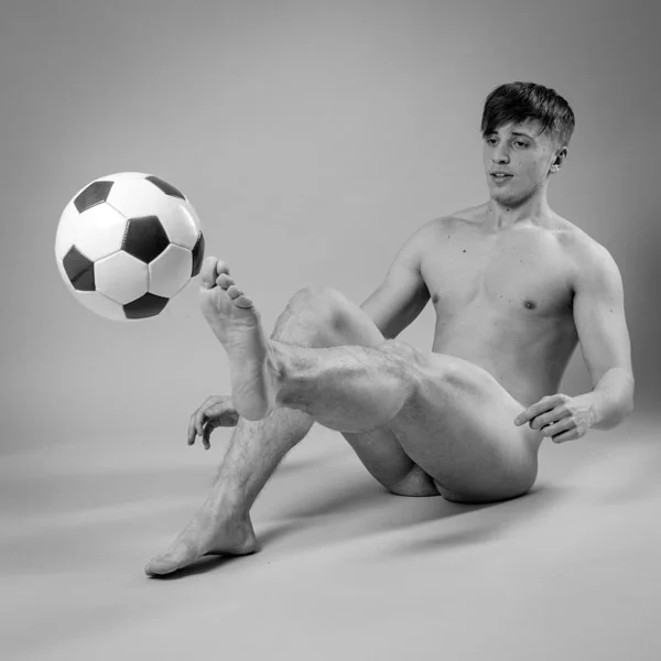 black and white image of nude man playing with football