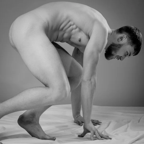 black and white image of nude man who has bent over