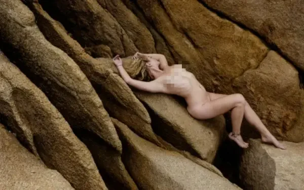 female model posing nude on rocks
