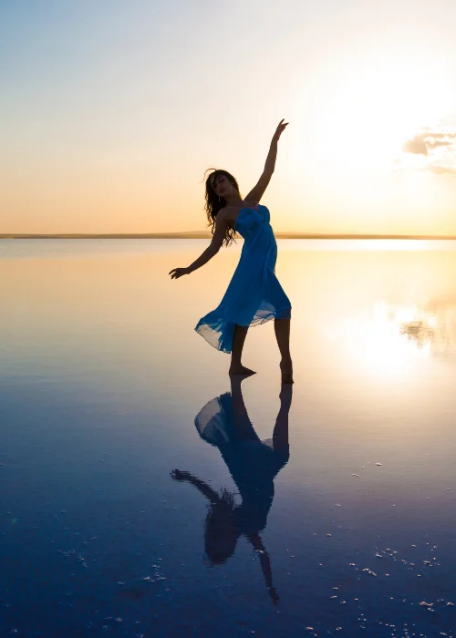 a woman dancing while the sun sets