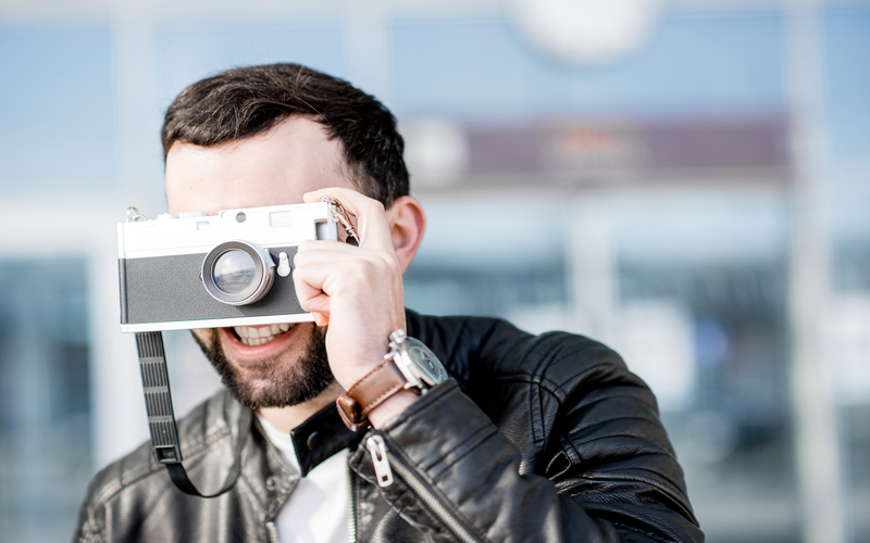 Man in leather jacket photographing with photo camera