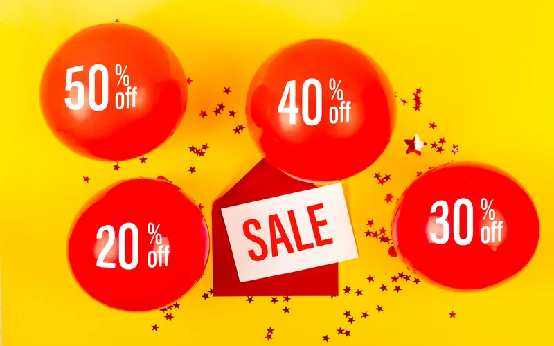 red balloons and star confetti on yellow - sale banner