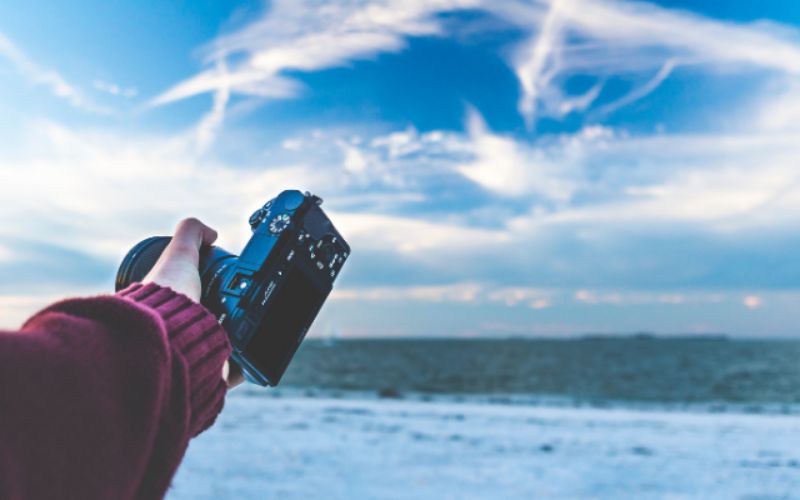 An image of a person holding a camera in hand