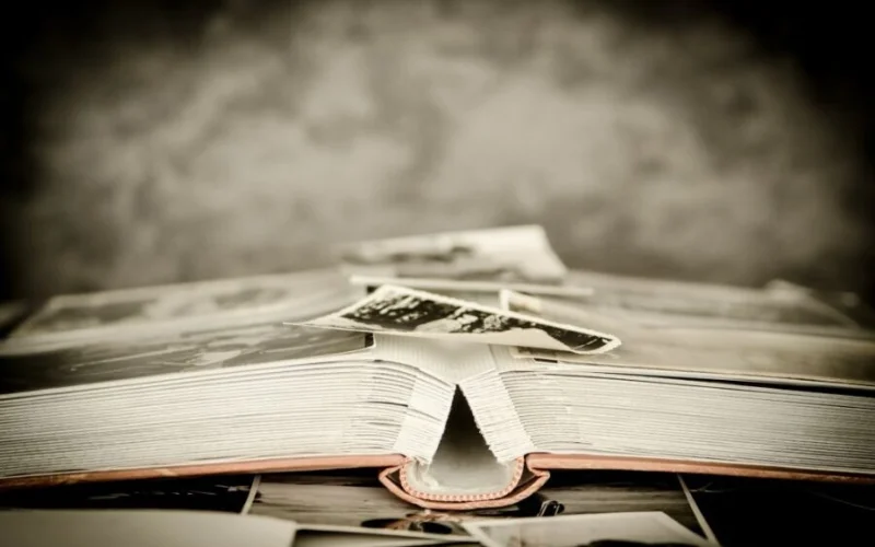 An image of an opened book with photographs lying on top
