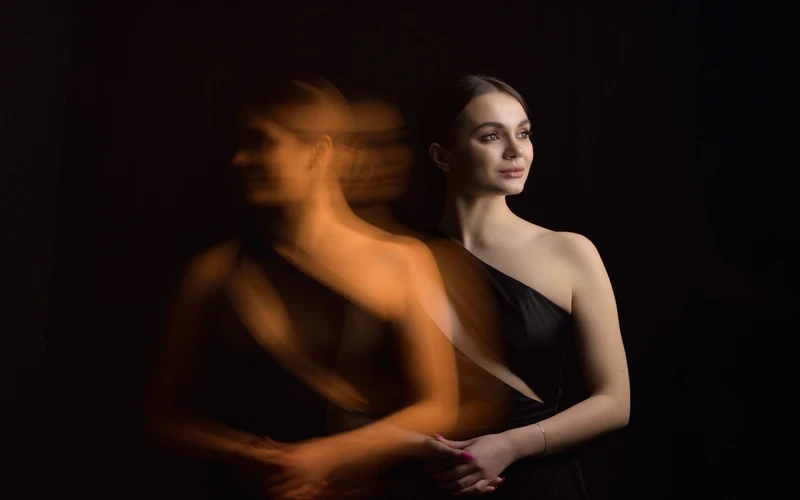 Woman photographed with a motion blur light trail effect against a dark background
