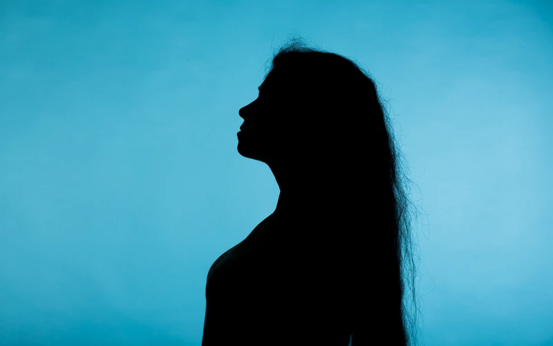 Silhouette of a woman's profile against a teal background, an example of fine art figure photos