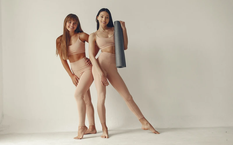 Two women posing together in nude-tone outfits, an example of human figure photography with multiple subjects