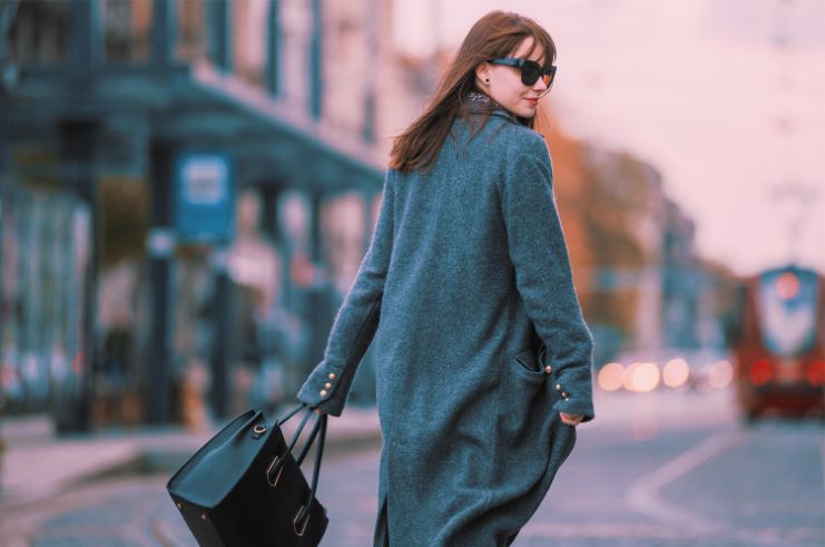 woman walking, looking over the shoulder wearing shades, a winter jacket