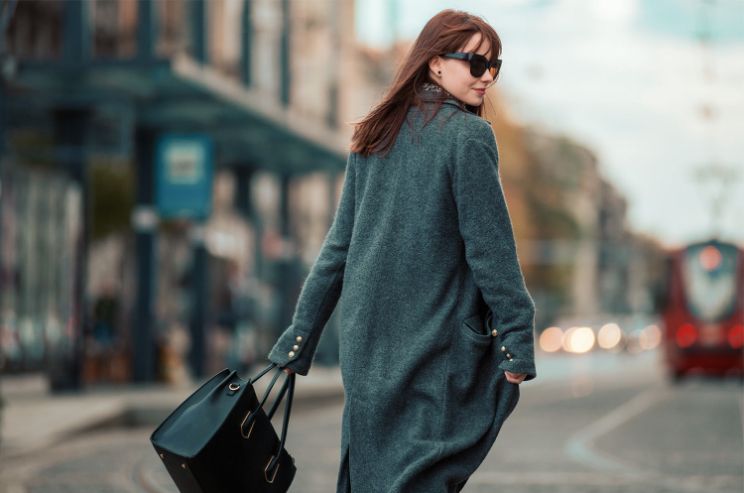woman walking, looking over the shoulder wearing shades, a winter jacket
