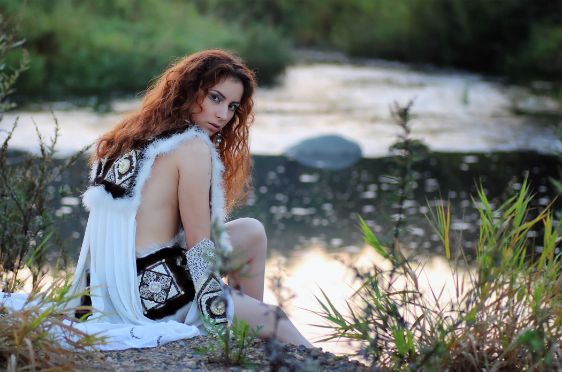 girl sitting on a rock wearing white clothes looking over the shoulder