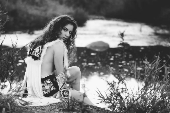 girl sitting on a rock wearing white clothes looking over the shoulder