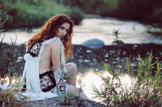 girl sitting on a rock wearing white clothes looking over the shoulder