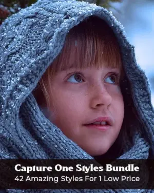 close up of a baby's face wearing a hoodie during snowfall,