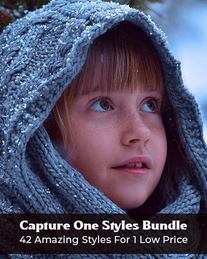 close up of a baby's face wearing a hoodie during snowfall,
