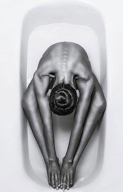 nude pose in bathtub with legs and hands stretched