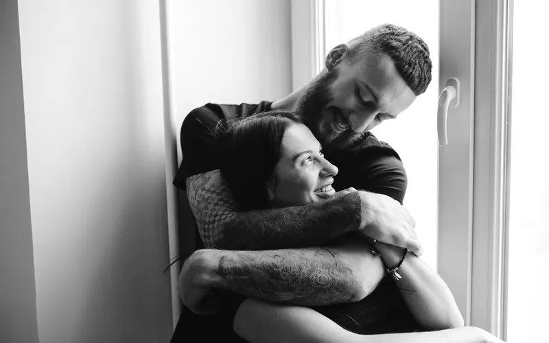 Boudoir couples picture of an affectionate couple embracing each other by the window