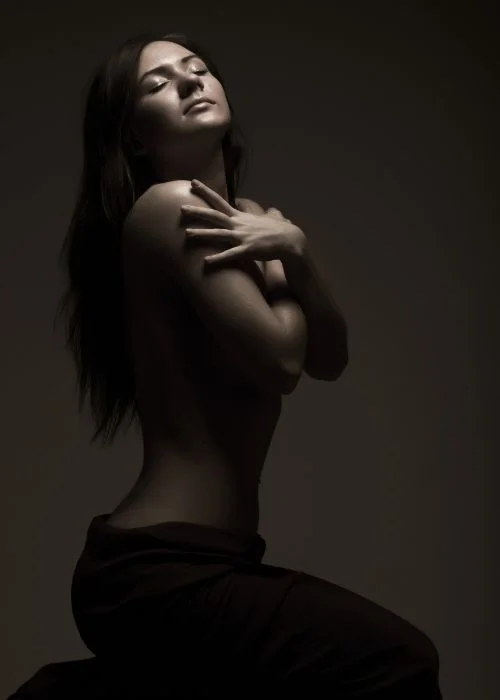 Fine art nude portrait highlighting natural curves with dramatic shadow play
