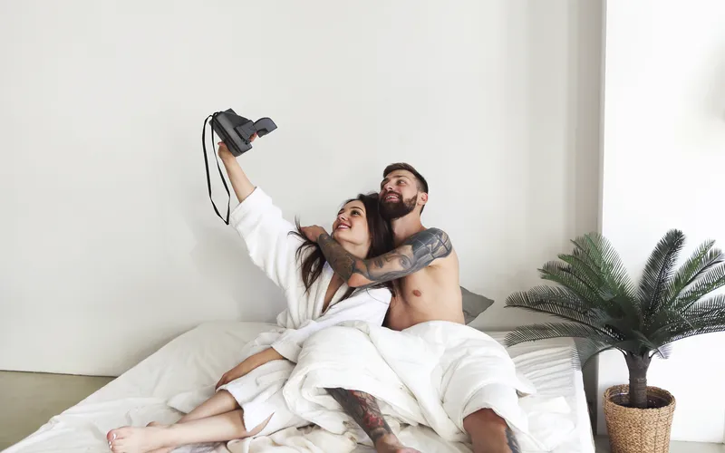 picture of a couple in bathrobes taking a photo with camera