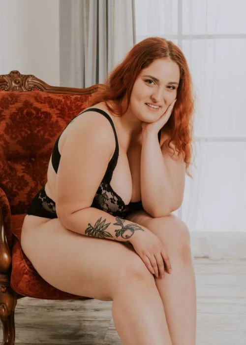 Stylish plus size boudoir pose with cozy fabrics and soft natural light