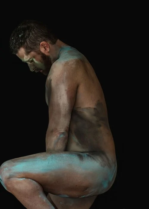 Artistic male nude pose with dramatic side lighting and fine art composition
