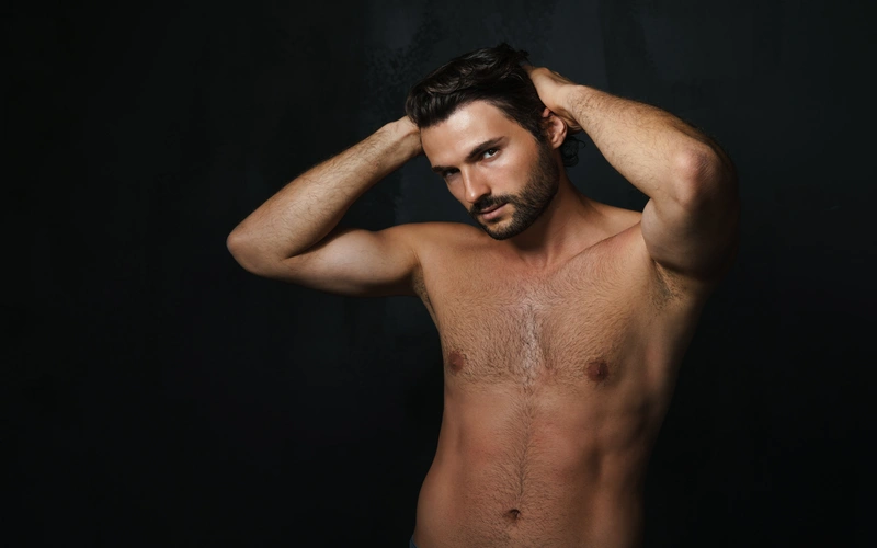 Man posing for his boudoir photoshoot with arms raised