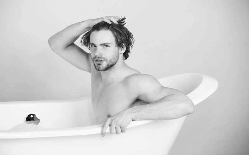 Monochrome image of a man sitting in a bathtub