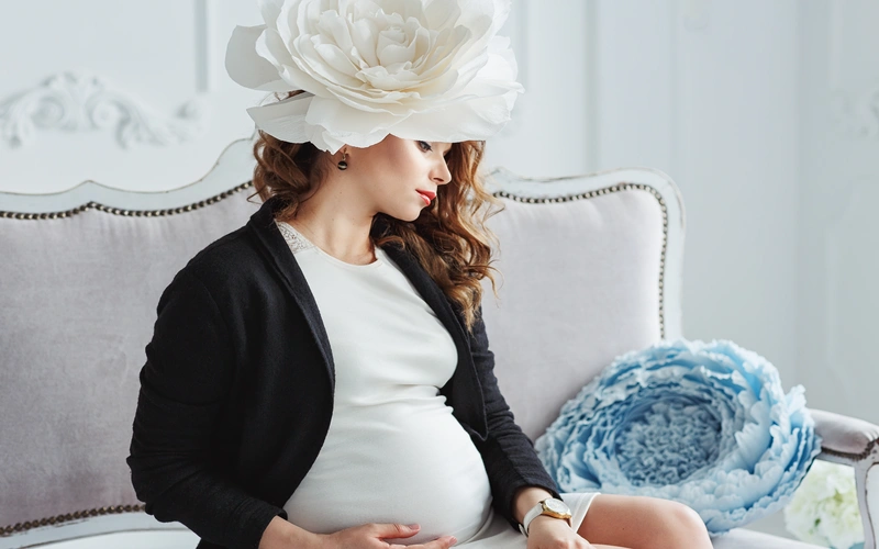 pregnant woman posing with a giant white flower crown on her head