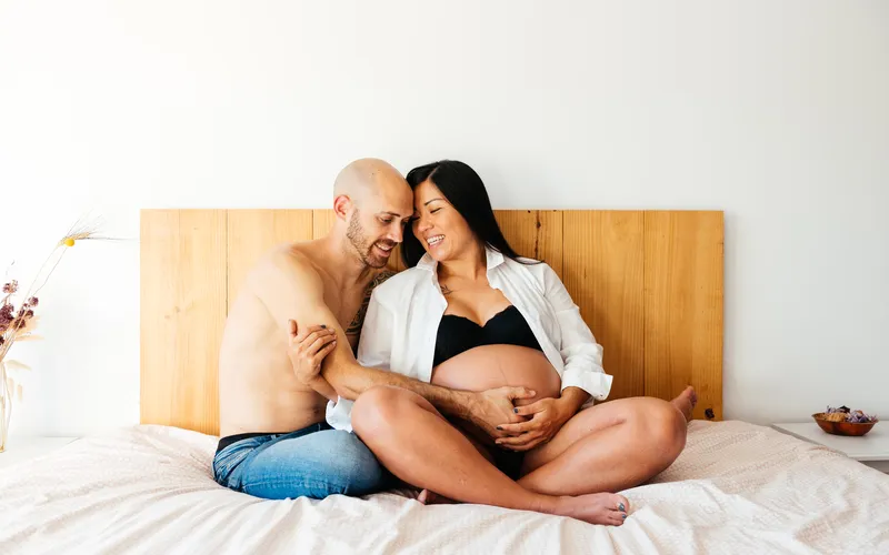 Boudoir pregnancy photoshoot of an expecting couple on the bed
