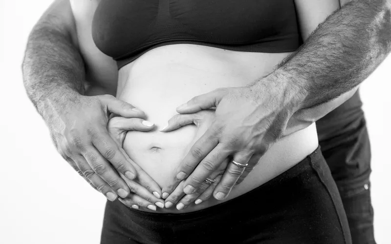 Boudoir pregnancy shoot while making hearts with hands