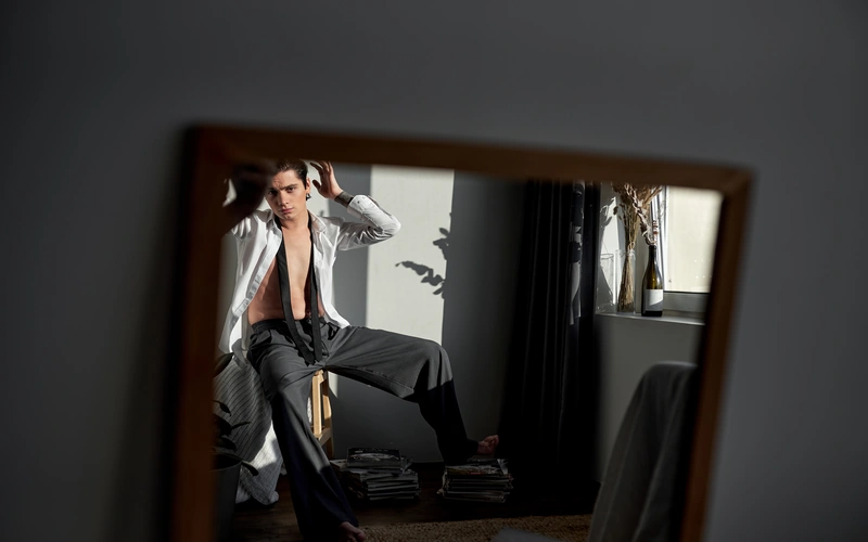 Boudoir pose of a man using a mirror