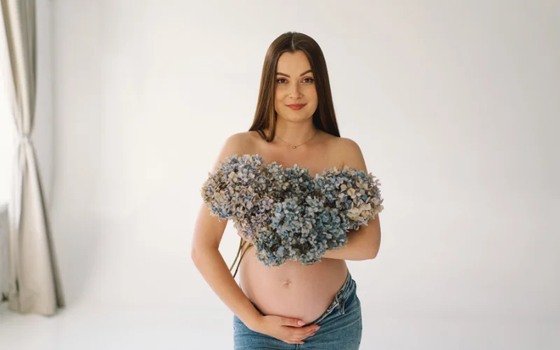 Boudoir pregnancy photoshoot of a woman holding flowers