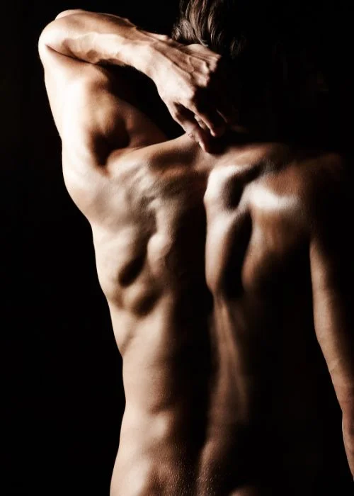 Male nude photography pose featuring relaxed posture and emotional expression