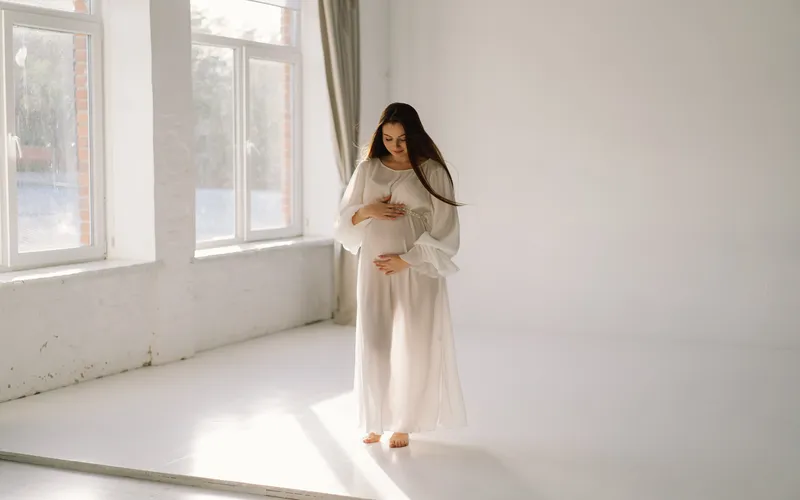 pregnant woman in a sheer white dress boudoir maternity photoshoot