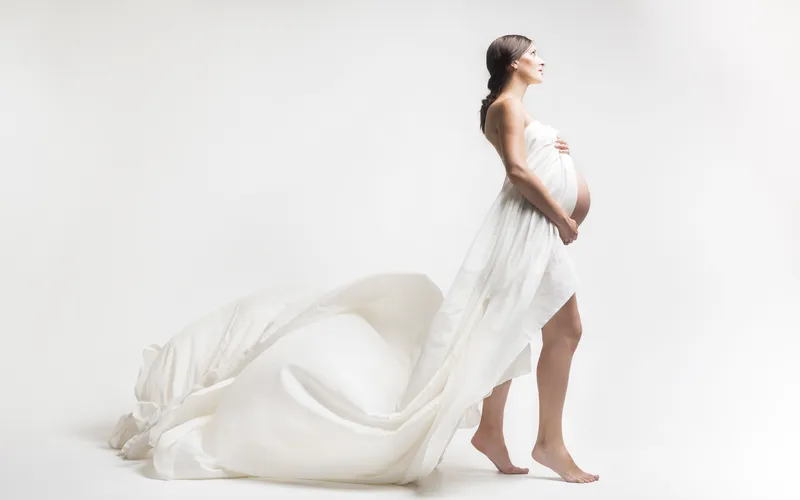 woman posing with white curtain for her Boudoir maternity photoshoot