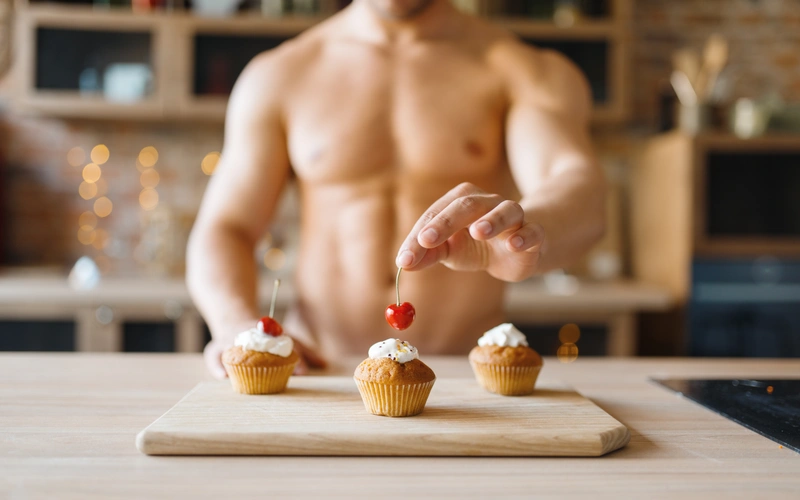 A man is putting cherries on the cupcakes