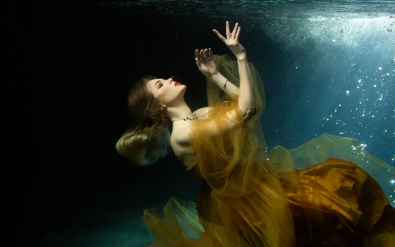 Model floating on her back in a relaxed underwater posing style.