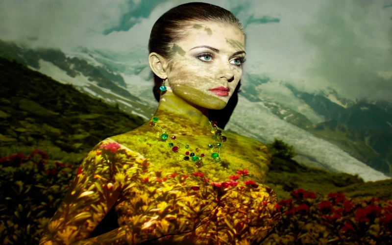 Woman lit with green and gold colored gels, double exposed with a mountain landscape