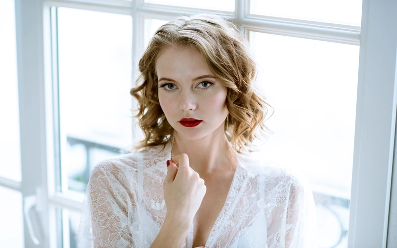 A woman in a white lace robe posing for her boudoir photoshoot
